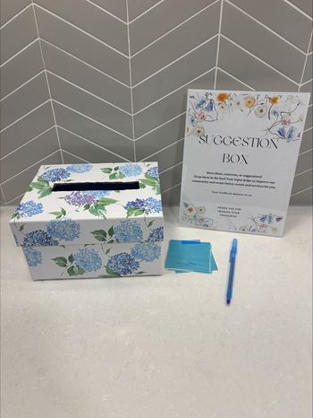 A box with a floral pattern and a suggestion box with a pen on the side.